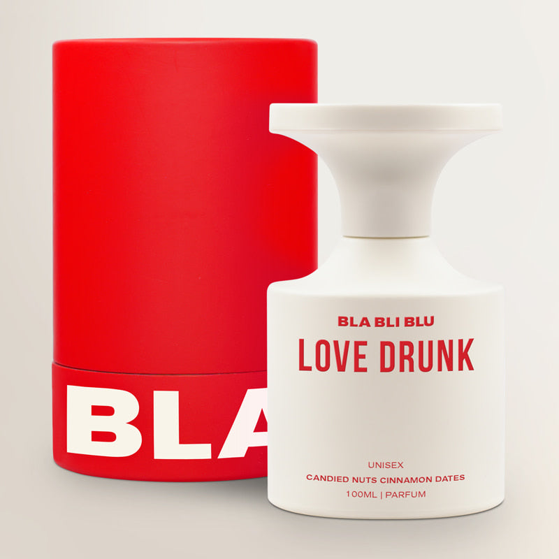 White perfume bottle labeled 'BLA BLU LOVE DRUNK' with a red container in the background.